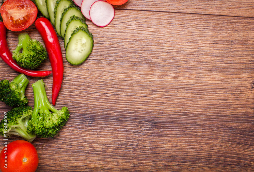 tomato, radish, cucumber, broccoli, onion, chili on a wooden surface. arrangement of sliced vegetables. Top view with copy space for text. Top view with copy space for text tomato, radish, cucumber, broccoli, onion, chili on a wooden surface. arrangement of sliced vegetables. Top view with copy space for text. Top view with copy space for text