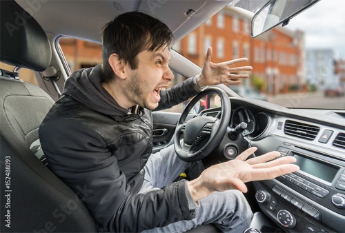 Φωτογραφία Angry young driver is driving a car and shouting.