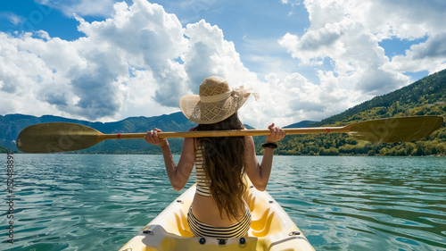 Young woman with long hair and hat resting during kayaking on lake