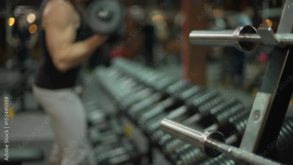 Fit guy doing alternative lift-ups with dumbbells in gym, weight lifting Fit guy doing alternative lift-ups with dumbbells in gym, weight lifting