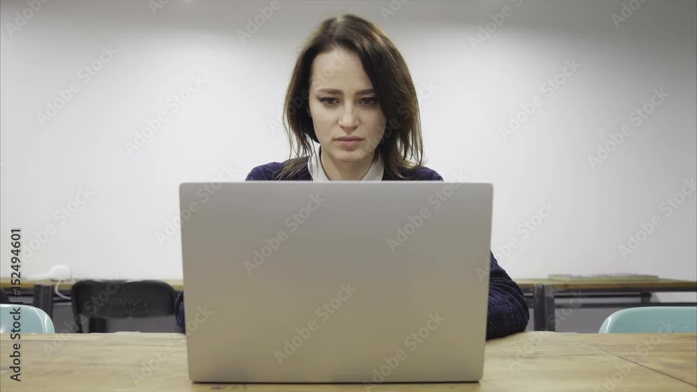 Tired woman is working late in the empty office, closing a laptop and putting the head on the table Tired woman is working late in the empty office, closing a laptop and putting the head on the table