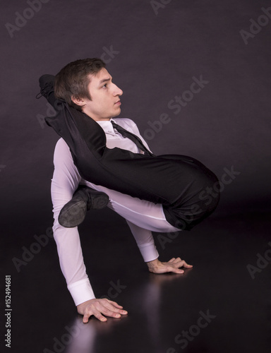 Extraordinary gymnast on a black background. The man with no bones. Studio photography of circus performers