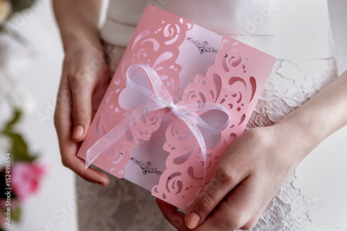 Wedding invitation pink card In the hands of the bride