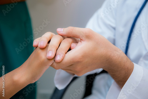 Friendly male doctor hand holding patient hand sitting at the desk for encouragement - empathy - cheering and support while medical examination. © N_studio