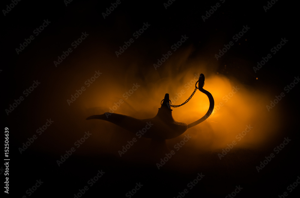 Obraz premium Antique arabian nights style oil lamp with soft light white smoke, Dark background. Lamp of wishes concept. Toned
