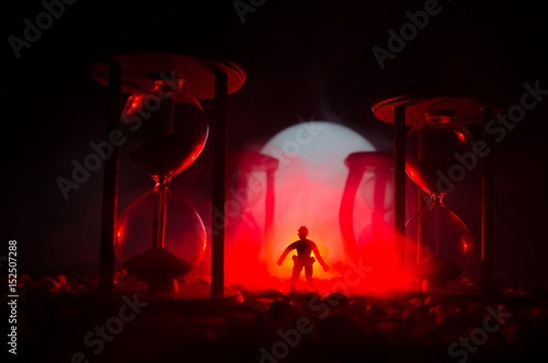 Time concept. Silhouette of a man standing between hourglasses with smoke and lights on a dark background.