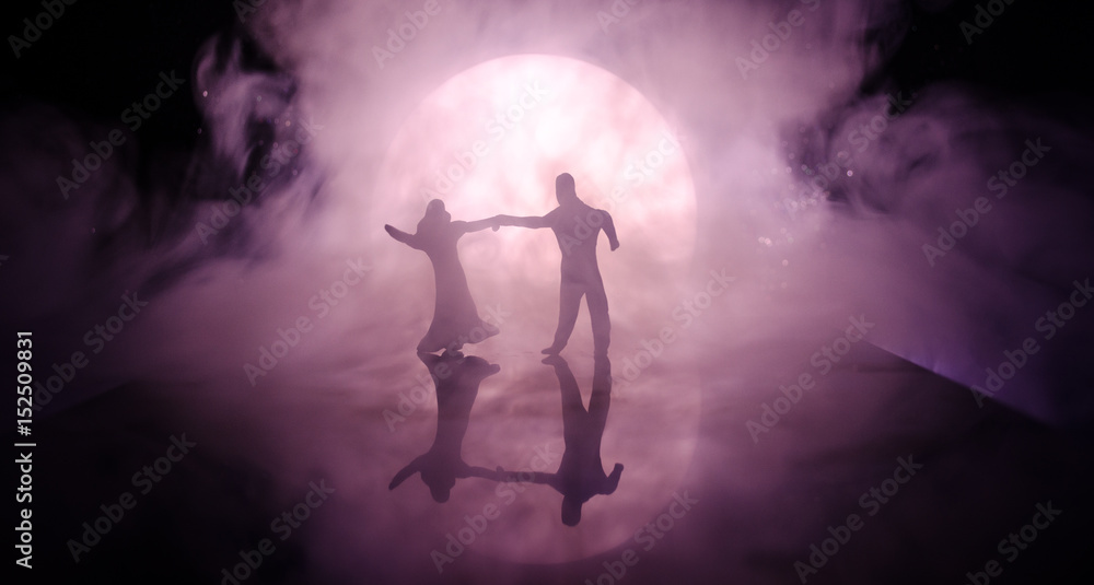 Silhouettes of toy couple dancing under the Moon at night. Figures of ...