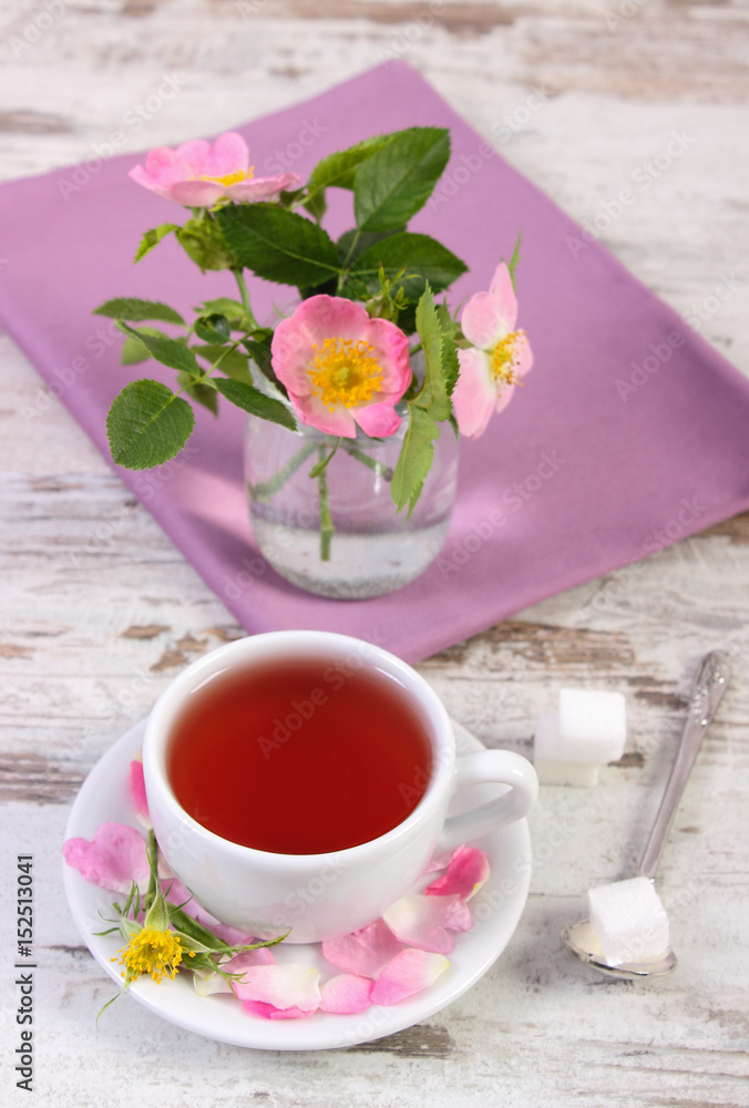 Cup of tea and wild rose flower on rustic wooden background Cup of tea and wild rose flower on rustic wooden background