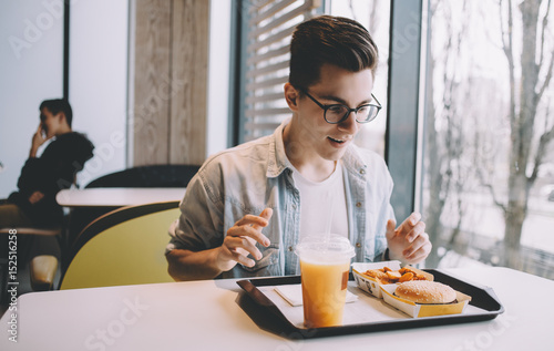 Handsome young man having lunch in cafe alone