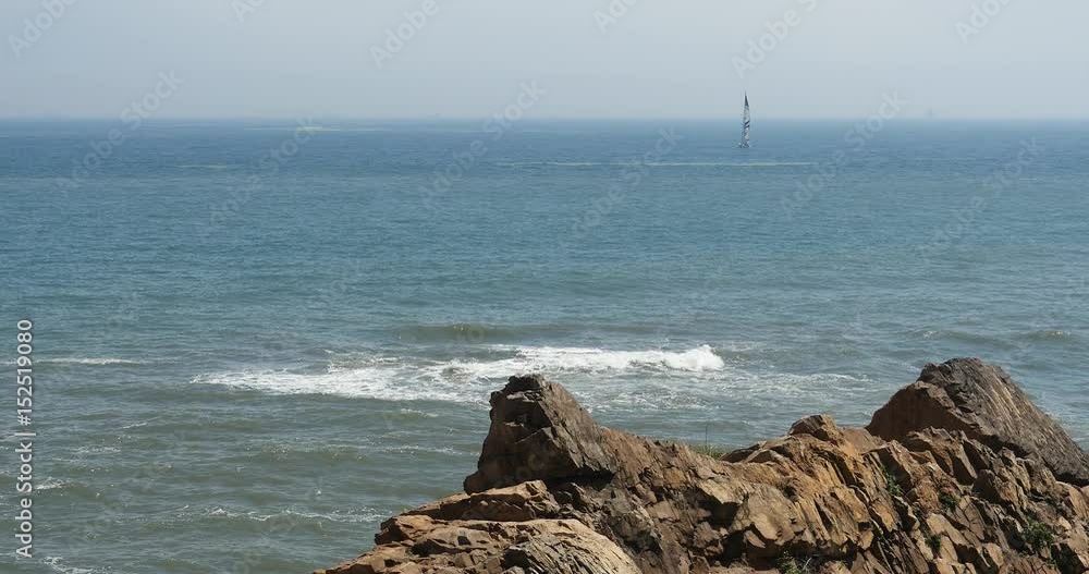 4k sailboat sailing in the wide ocean,sparkling sea water waves surface & coastal rock reef coast surge shore. 4k sailboat sailing in the wide ocean,sparkling sea water waves surface & coastal rock reef coast surge shore.