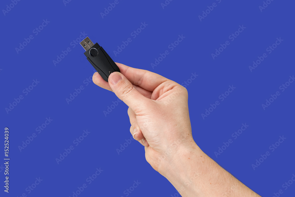Black USB flash drive on hand with isolated blue background Black USB flash drive on hand with isolated blue background