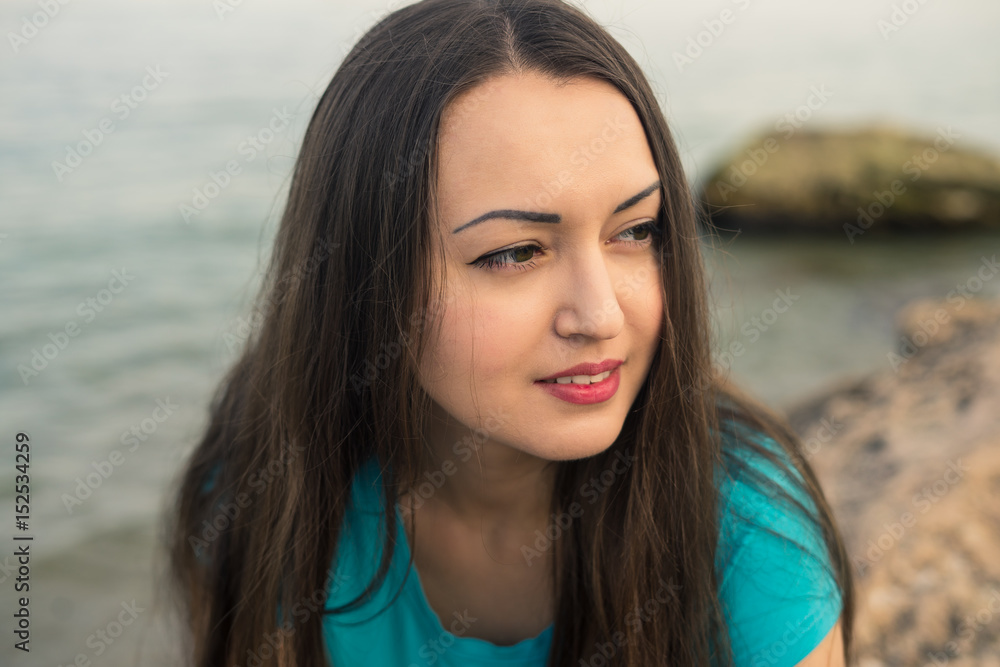 Close up portrait of beautiful young girl on the beach. She is looking for somebody