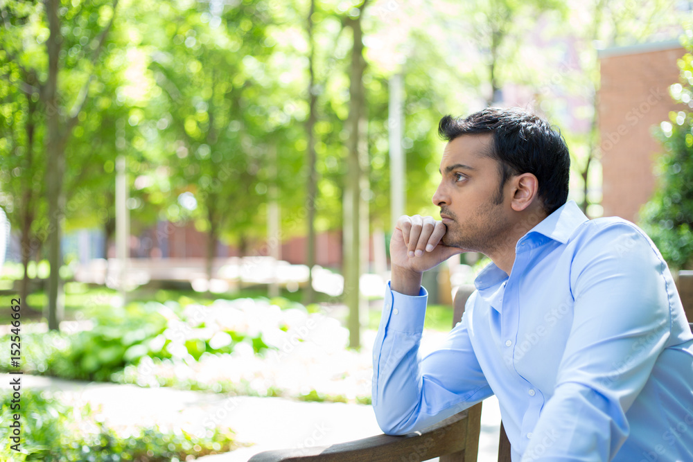 Closeup portrait, stressed young business man, hand on head, worried, isolated background of trees outside. Negative human emotion facial expression feelings. Closeup portrait, stressed young business man, hand on head, worried, isolated background of trees outside. Negative human emotion facial expression feelings.
