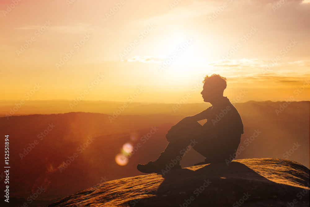Silhouette of a man standing and rise his hands up in the air during sunset Silhouette of a man standing and rise his hands up in the air during sunset