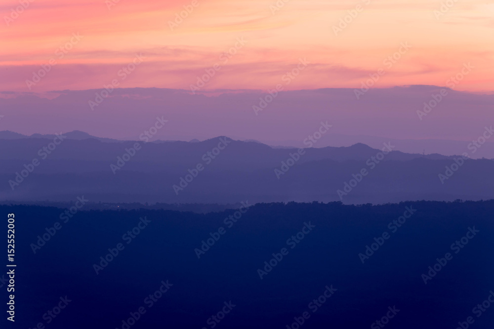 Silhouettes of the mountain hills layer in the morning mist. Colorful summer scene.