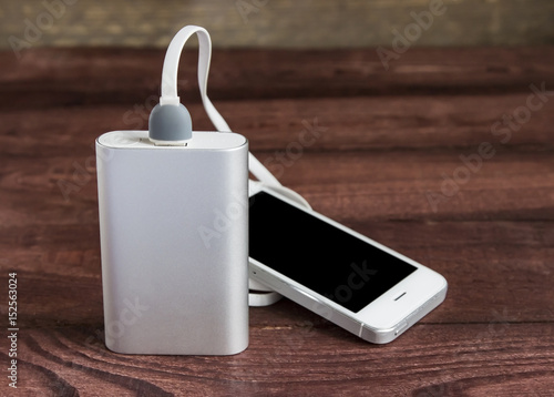 Charging smartphone with power bank on wooden background