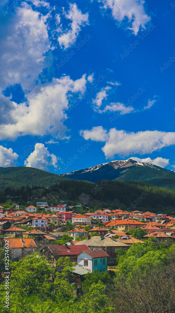 Photo depicting a beautiful colorful amazing Bulgarian mountain village landscape, summertime. Europe, Bulgaria, Dobarsko mountain village landscape, bathed in sunshine on a blue sky background.