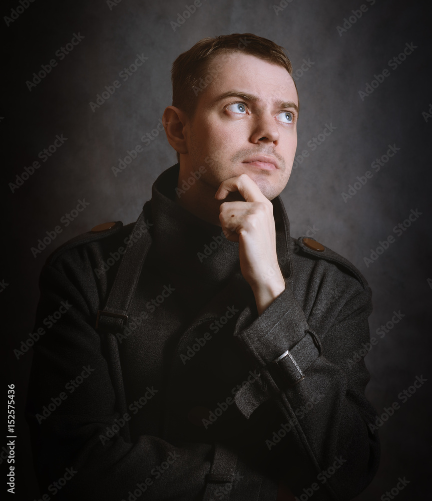 Young man in coat on dark background. Color toned. Young man in coat on dark background. Color toned.