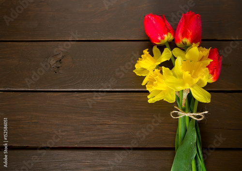 yellow daffodils and red tulips on dark wooden surface