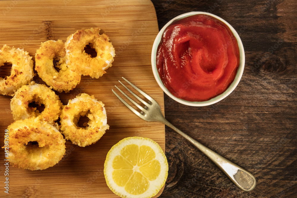 Calamari rings, red sauce, fork, lemon, copyspace