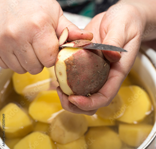 The cook cleans the potatoes with a knife