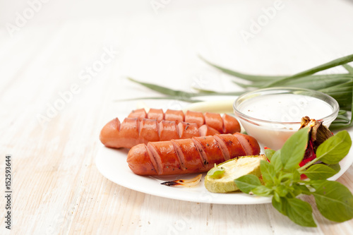 Fried sausages on the barbeque grill on a white