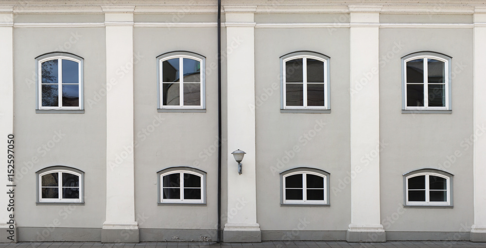 Fototapeta premium Five white columns, eight plastic windows and one streetlight make a wall of the restored ancient house.