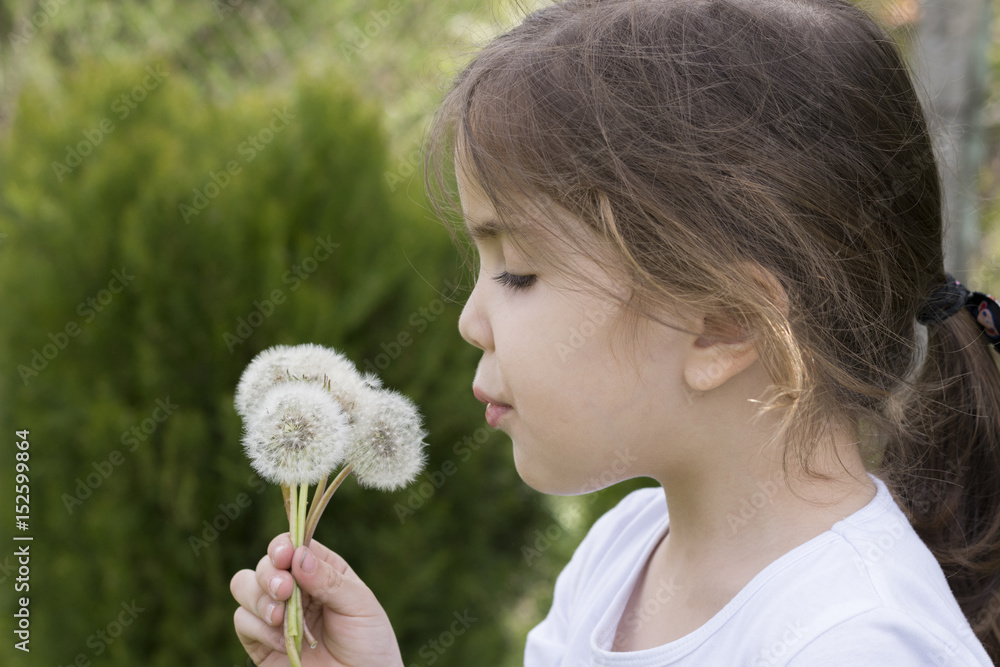 Little cute girl blowing dandelions. Green background. Closeup. Little cute girl blowing dandelions. Green background. Closeup.