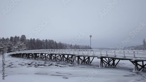 Walking bridge over  icy lake in snowfall  