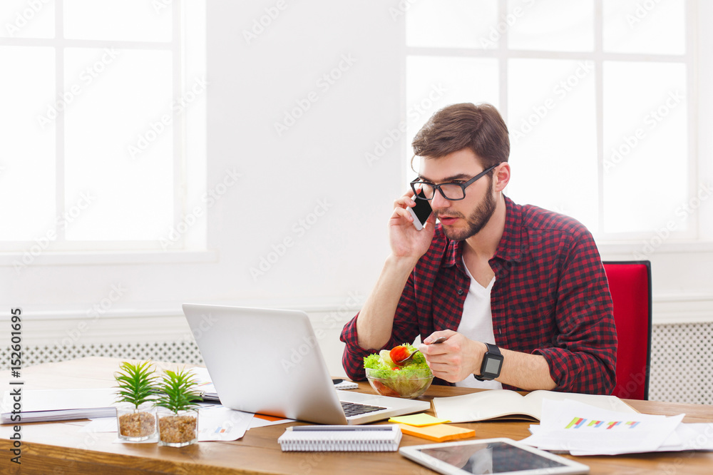 Busy man has business lunch in modern office interior Busy man has business lunch in modern office interior