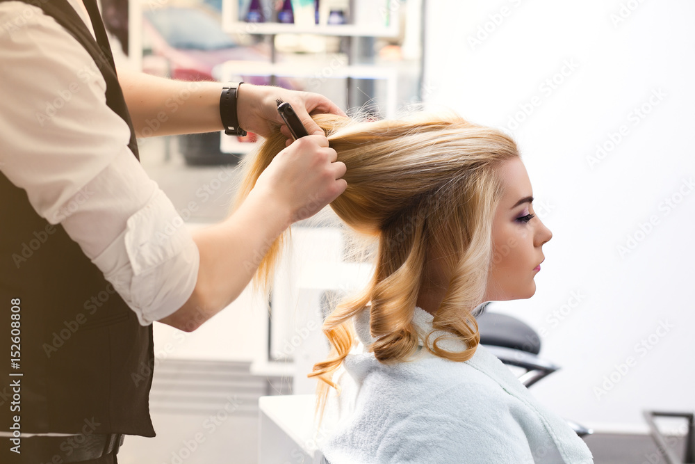 handsome Hairdresser does a hairstyle for a blonde girl in a beauty salon handsome Hairdresser does a hairstyle for a blonde girl in a beauty salon