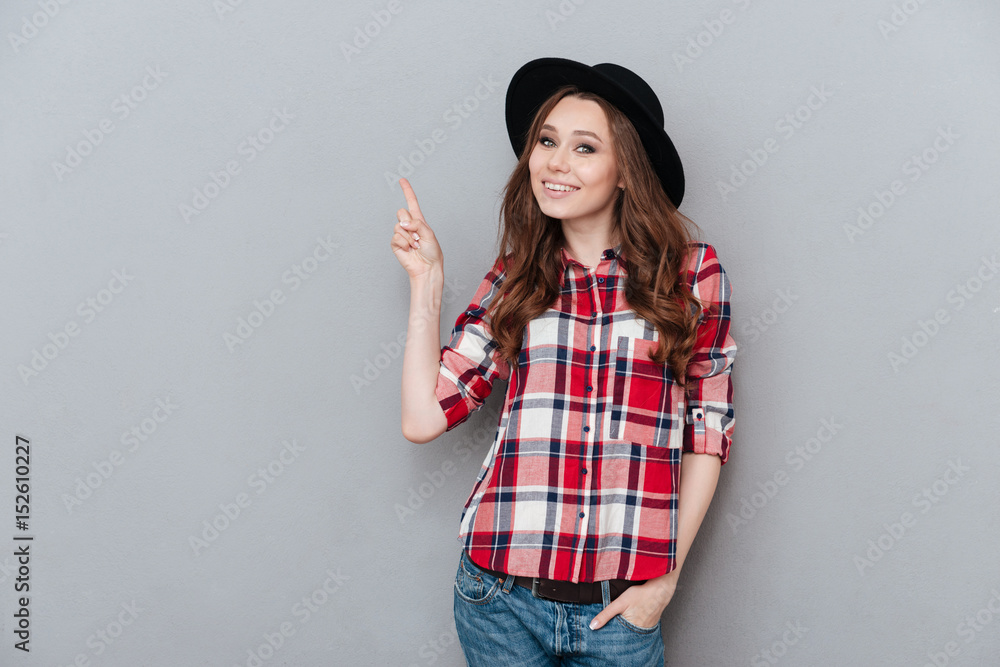 Cheerful girl in plaid shirt pointing finger up at copyspace Cheerful girl in plaid shirt pointing finger up at copyspace