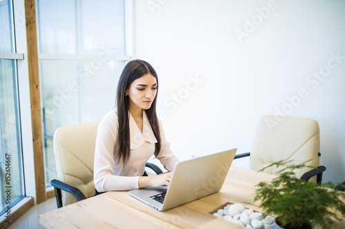 Portrait of a serious businesswoman using laptop in modern office