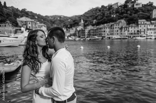  happy groom and bride in white dress hugging sea background © VAKSMANV