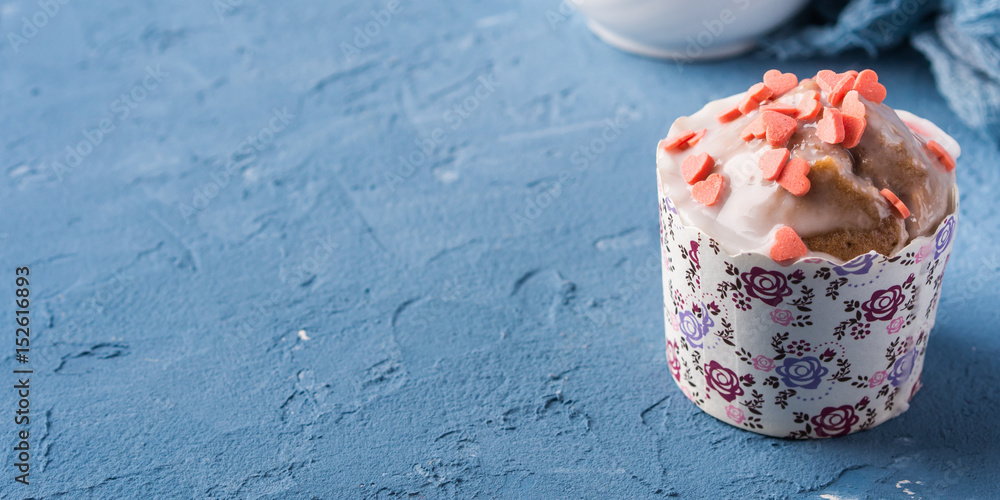 Cup of tea on blue background with frosted cup cake, flowers and textile Cup of tea on blue background with frosted cup cake, flowers and textile