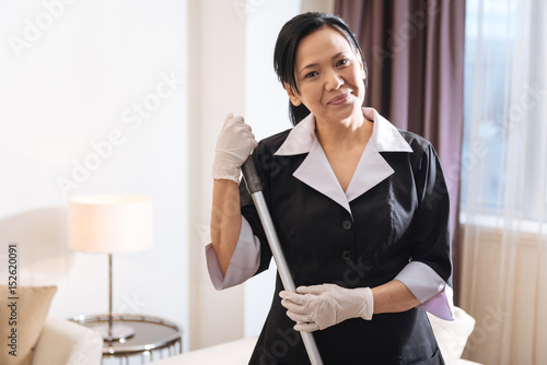 Delighted positive chambermaid looking at you photo