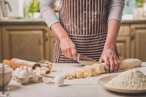 Close-up view of two woman's hands cut knife dough