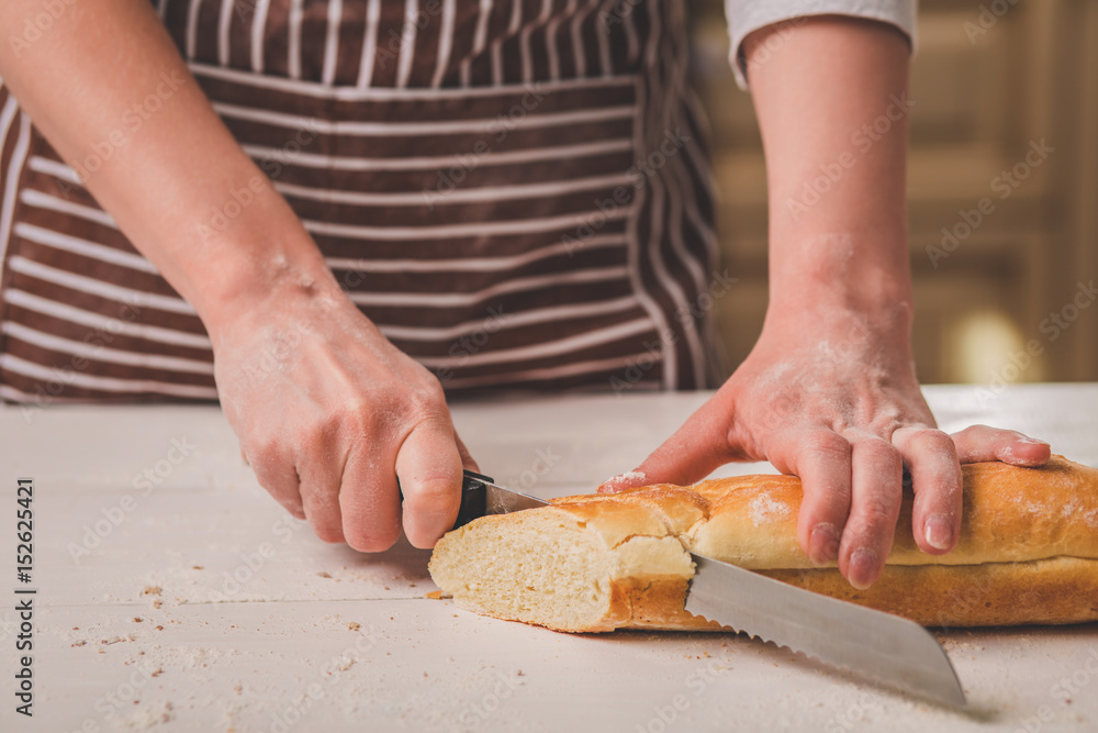 Woman cutting bread on wooden board. Bakehouse. Bread production.
