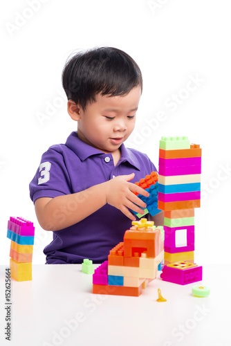 Kid boy playing with blocks from toy constructor isolated