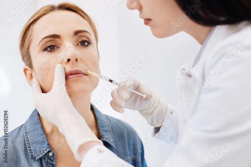 Professional female cosmetologist doing botox injections