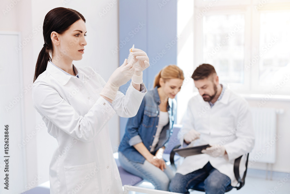 Serious pleasant woman looking at the syringe Serious pleasant woman looking at the syringe
