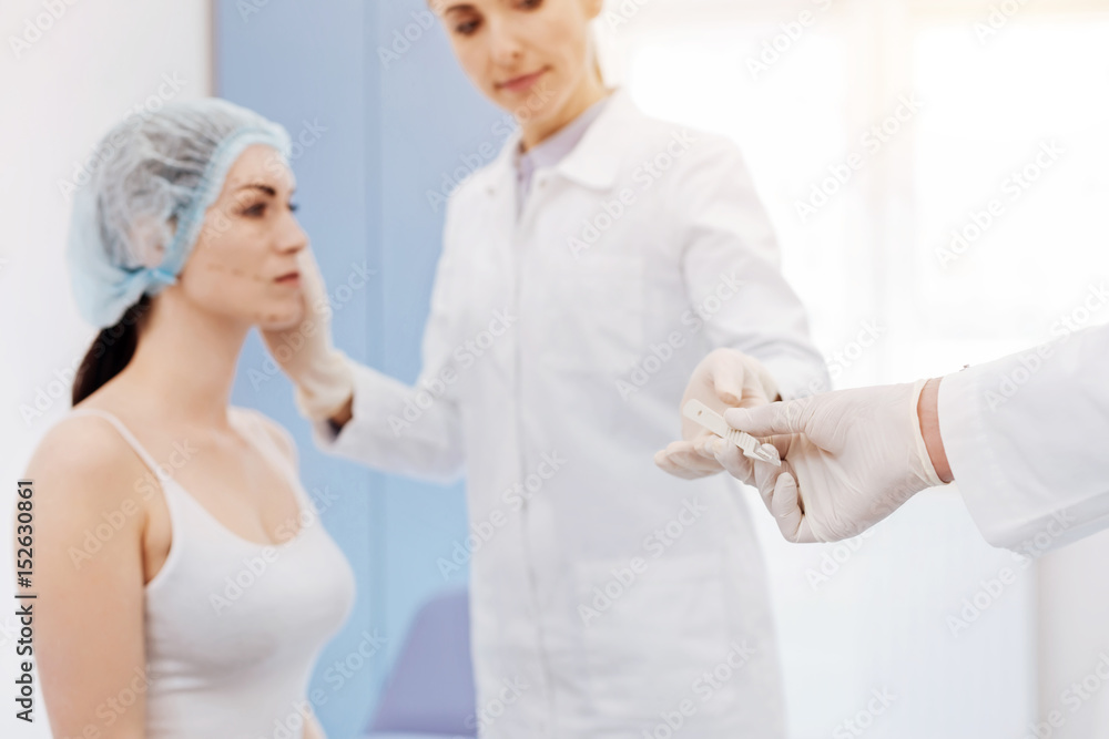 Medical tool being given to a plastic surgeon Medical tool being given to a plastic surgeon