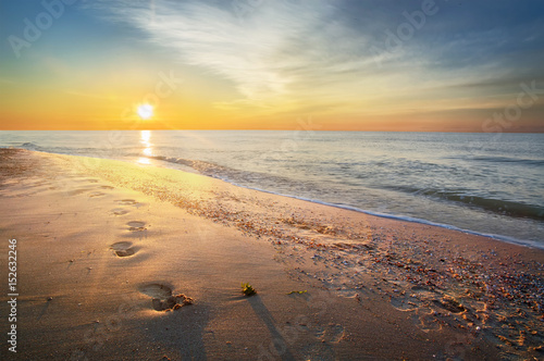 Footprints on the beach, dawn on the sea