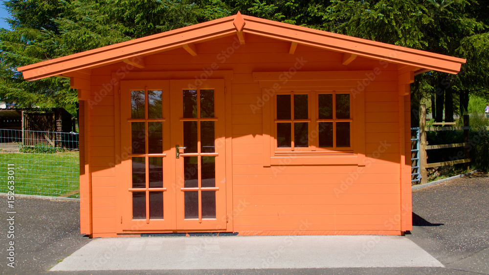 Peach coloured wooden summerhouse in sunlight.