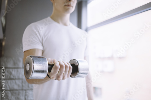 Young sportsman doing workout with dumbbell