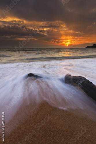 Beautiful pattern of waves surrounding a dead wood at the beach. The moment captured in long exposure.