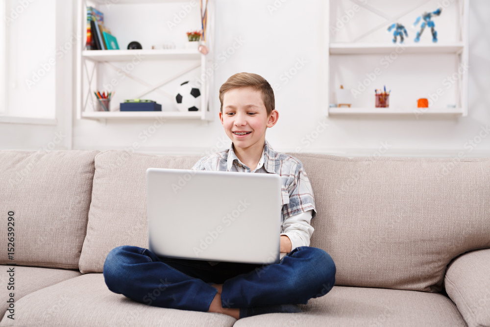 Teenage boy using laptop on couch at home Teenage boy using laptop on couch at home