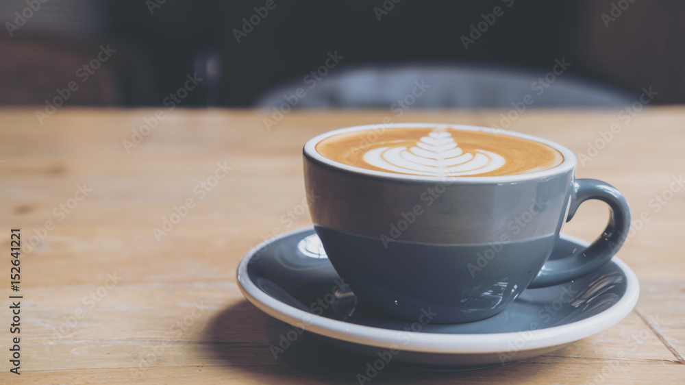 Closeup image of hot latte coffee with latte art on vintage wooden table Closeup image of hot latte coffee with latte art on vintage wooden table