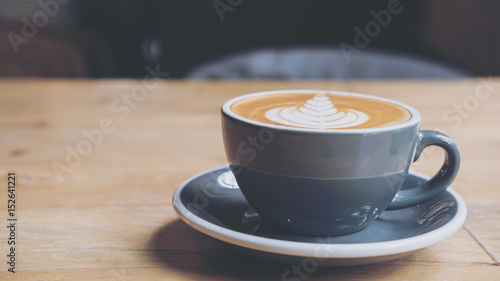 Closeup image of hot latte coffee with latte art on vintage wooden table