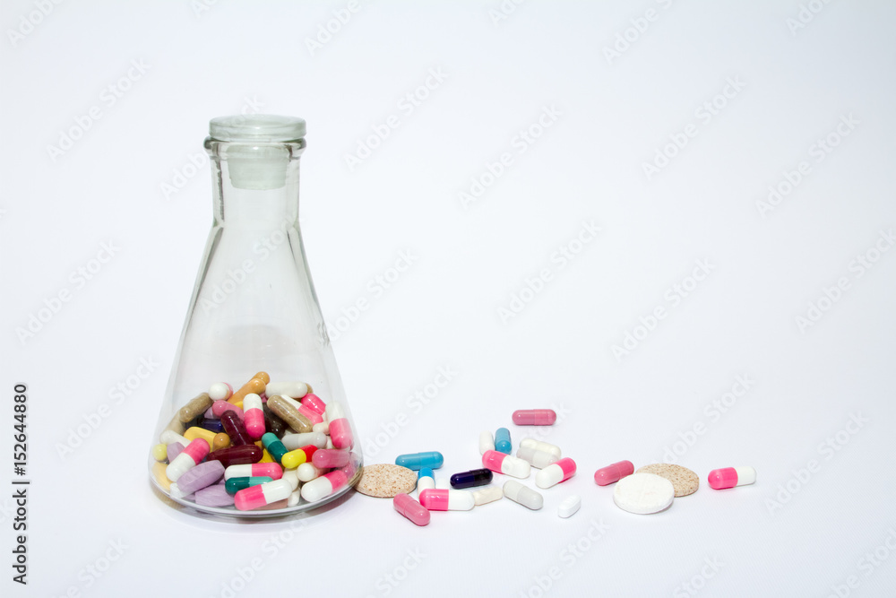 Colorful medical pills in a glass container on a white background. Colorful medical pills in a glass container on a white background.